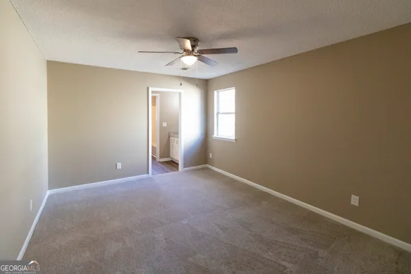 an empty room with windows and fan