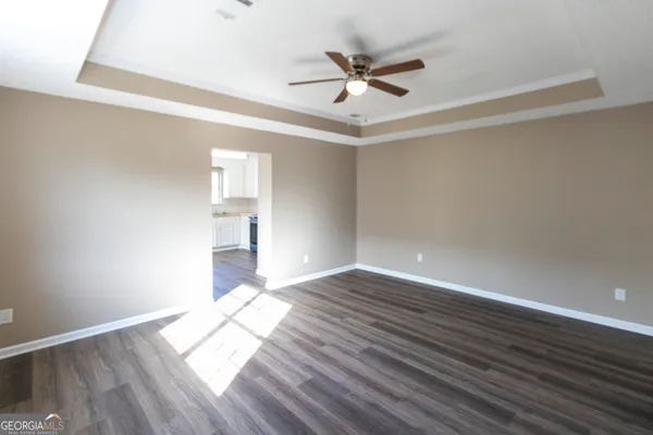 a view of empty room with wooden floor and fan