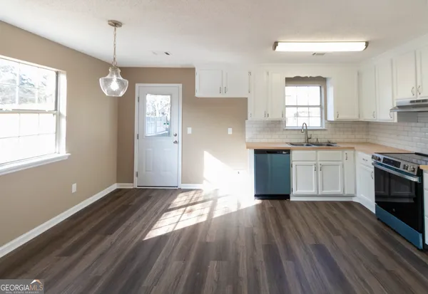 a kitchen with granite countertop a stove a sink and white cabinets with wooden floor