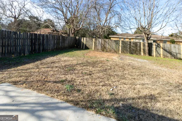 a backyard of a house with large trees and wooden fence