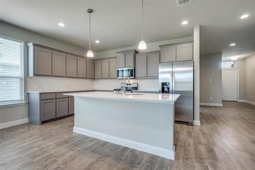 5231 Meadow Lane Krum, TX 76249 - Photo 3 of 17 Spacious kitchen featuring an expansive island with a white countertop, grey shaker-style cabinetry, stainless steel appliances, and wood-finish tile flooring