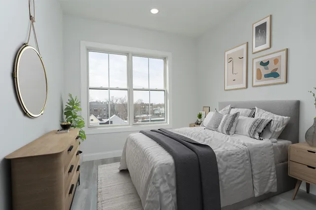 a bedroom with a bed a mirror and a large window