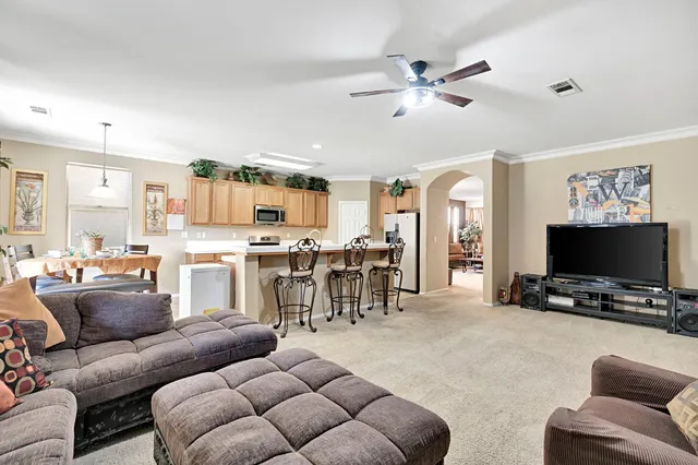 a living room with furniture kitchen view and a flat screen tv