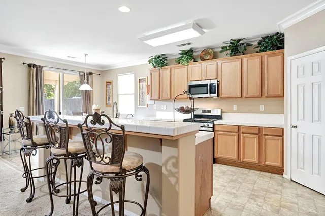 a kitchen with granite countertop a table chairs microwave and cabinets