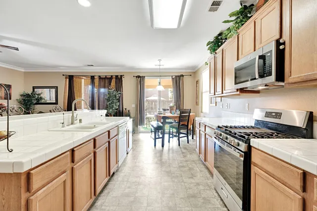 a kitchen with stainless steel appliances kitchen island granite countertop a stove a sink a dining table and chairs