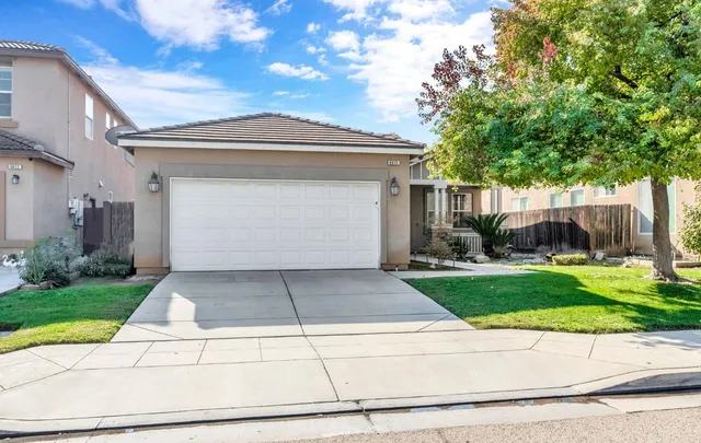 a view of a white house with a yard and a large tree