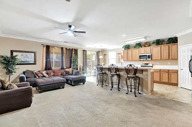 a living room with furniture and a large window with kitchen view