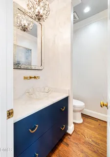 a kitchen with stainless steel appliances granite countertop a stove top oven a refrigerator a sink and white cabinets with wooden floor