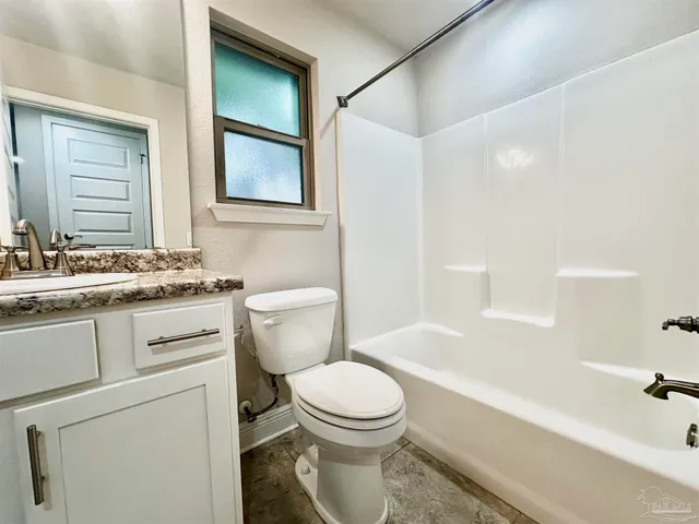 a bathroom with a granite countertop toilet sink and mirror