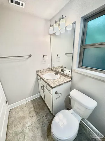 a bathroom with a granite countertop toilet sink and mirror