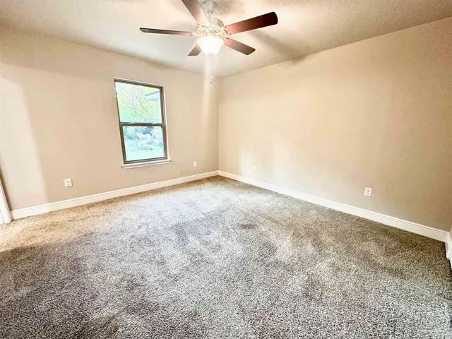 an empty room with windows and fan