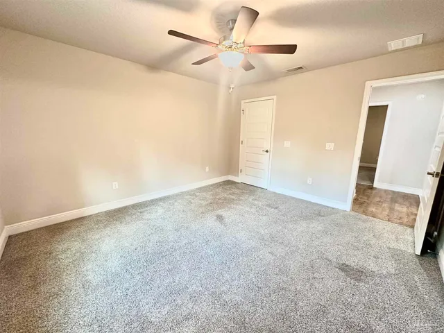 an empty room with a ceiling fan and a rug