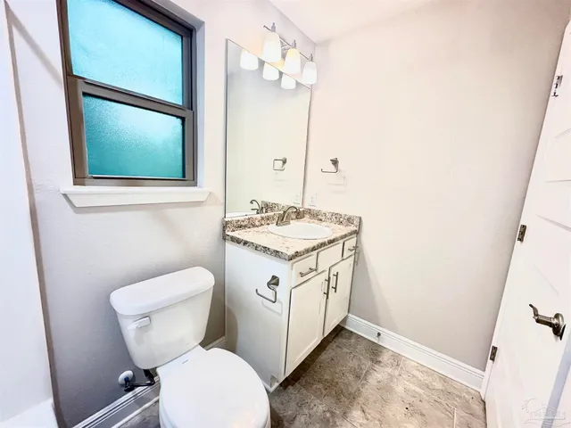 a bathroom with a granite countertop toilet sink and mirror