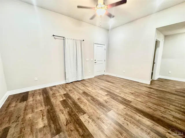 an empty room with wooden floor and fan