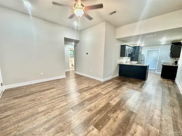 a view of a big room with wooden floor and chandelier fan
