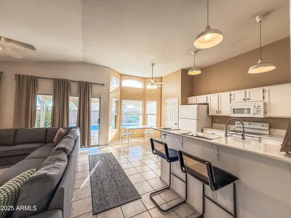 a large living room with stainless steel appliances granite countertop furniture a couch and a large window