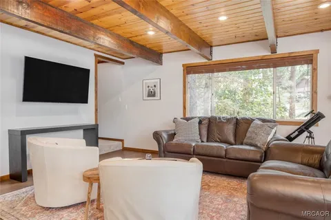 a living room with furniture a flat screen tv and a large window