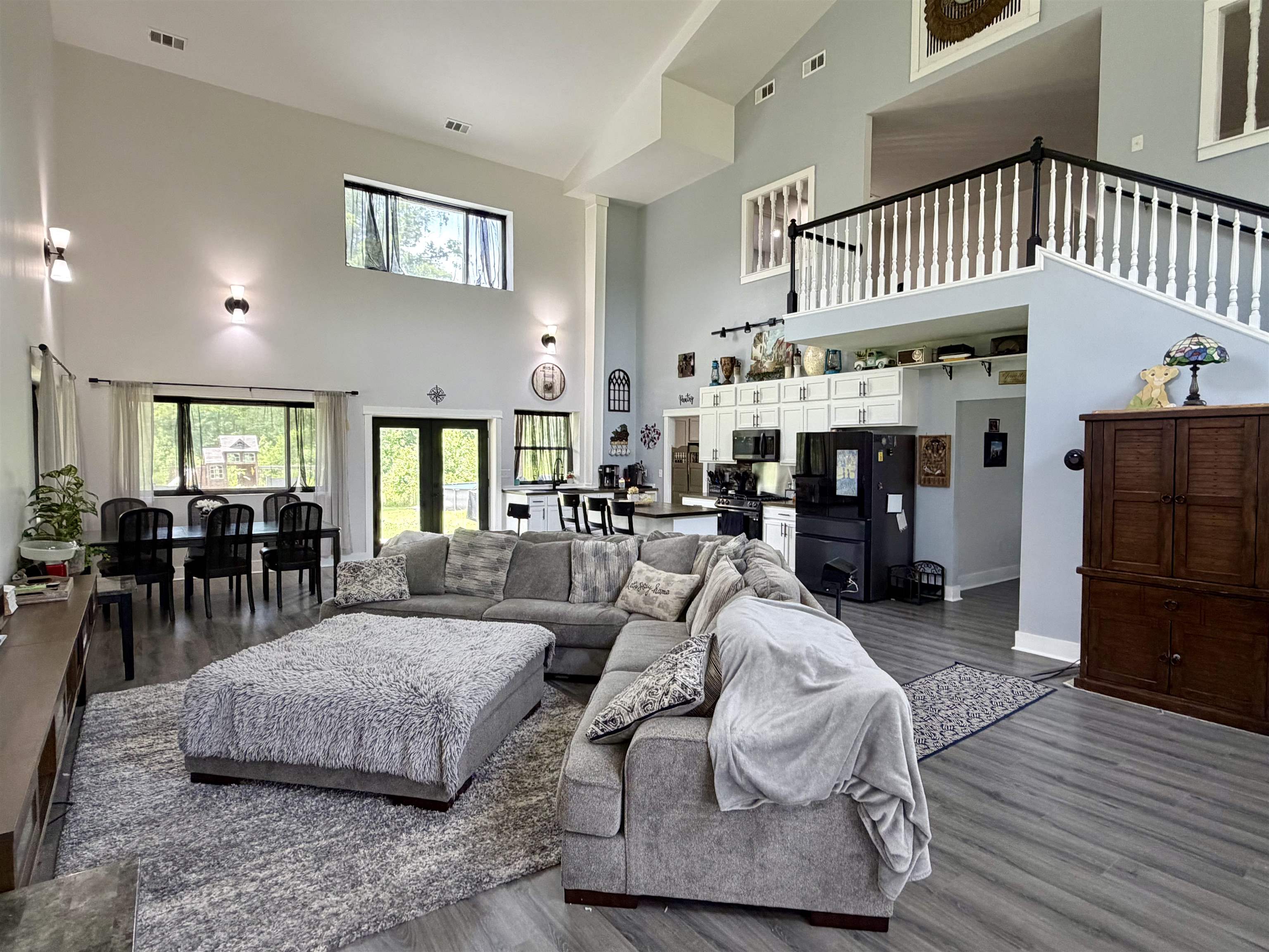 3670 Peavine Road Middleton, TN 38052 - Photo 2 of 36 Spacious living area featuring high vaulted ceilings, wood-finish flooring, and a second-story balcony with white balusters and a dark handrail