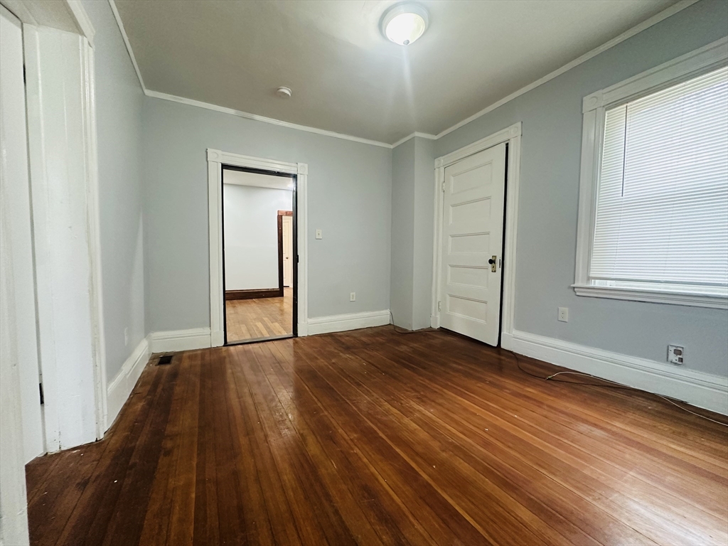 415 Washington Street, Unit 1 Boston, MA 02124 - Photo 6 of 9 a view of an empty room with wooden floor and a window