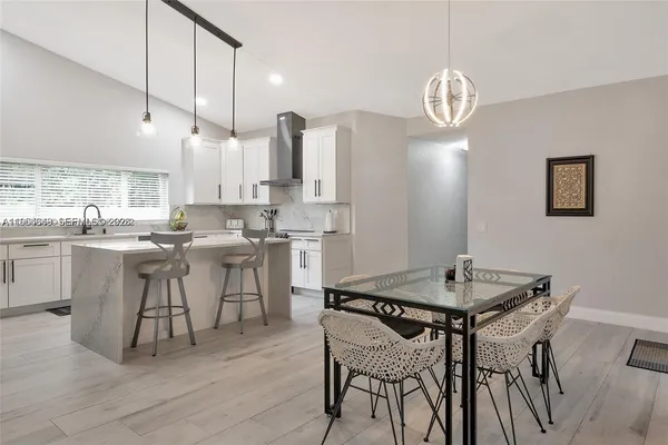 a kitchen with stainless steel appliances a table chairs refrigerator and cabinets