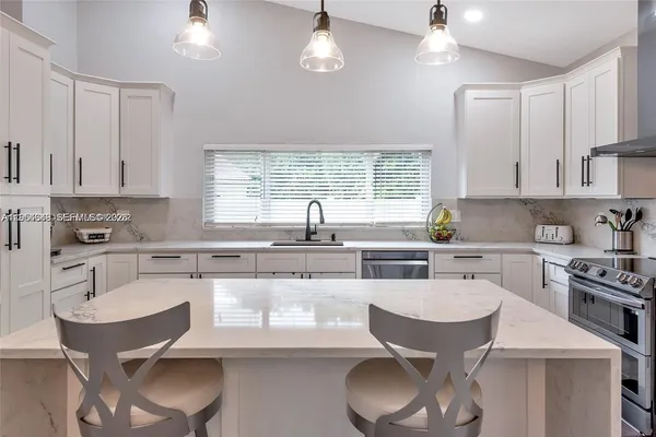 a kitchen with stainless steel appliances granite countertop a sink a stove a refrigerator cabinets and a dining table