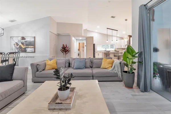 a living room with furniture couches and a dining table with wooden floor