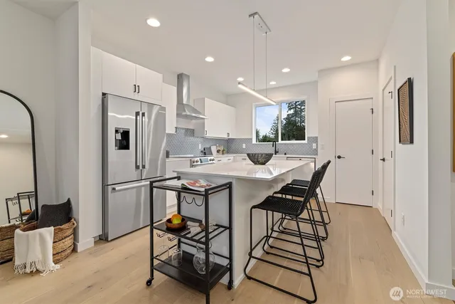 a kitchen with stainless steel appliances a refrigerator a sink dishwasher a stove and a dining table with wooden floor