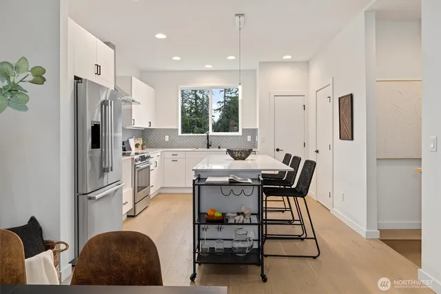a kitchen with stainless steel appliances granite countertop a dining table chairs refrigerator and sink