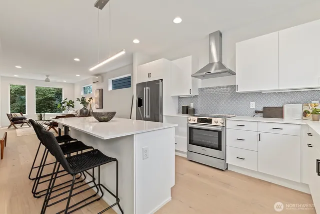 a kitchen with stainless steel appliances a sink a stove a refrigerator cabinets and chairs