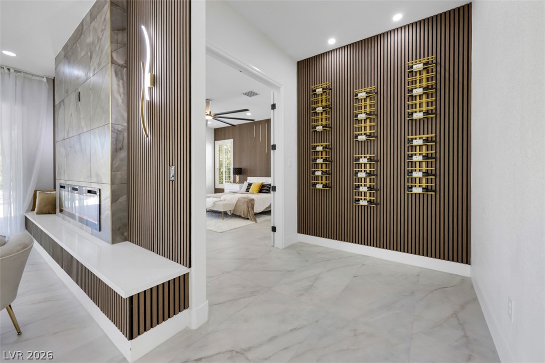 5015 Rivedro Street Las Vegas, NV 89135 - Photo 26 of 91 A refined interior showcases a linear fireplace with a bench, complemented by decorative slatted wood panels and recessed lighting.
