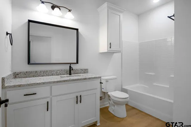 a bathroom with a granite countertop toilet a sink and a mirror