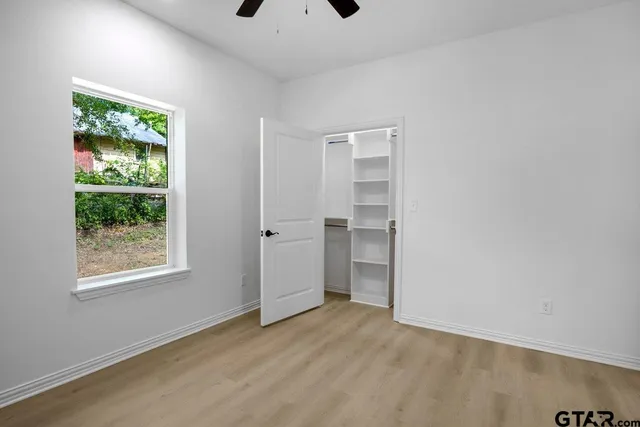a view of empty room with wooden floor and fan