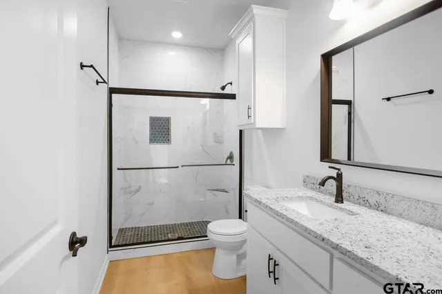 a bathroom with a granite countertop sink toilet and shower