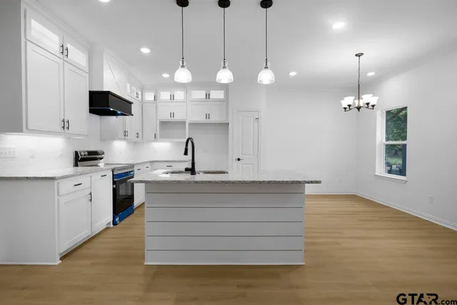 a kitchen with stainless steel appliances kitchen island a large island in the center and wooden floors
