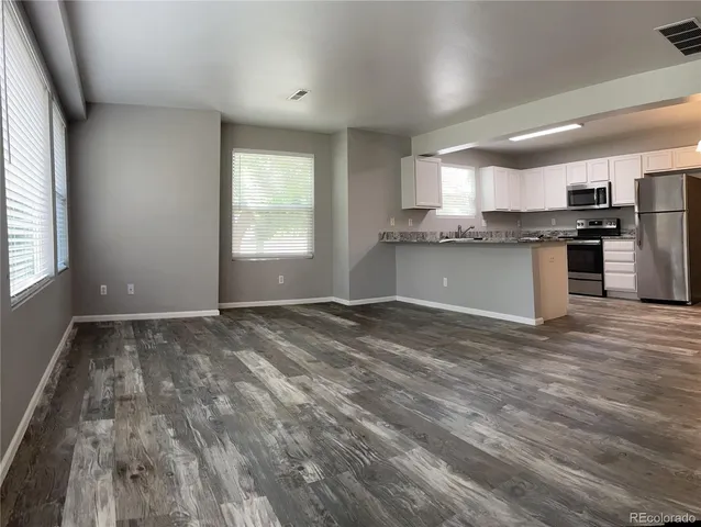 a view of a kitchen with a sink and dishwasher a refrigerator with wooden floor