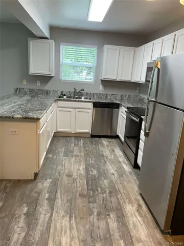 a kitchen with granite countertop a refrigerator a sink a stove a microwave and island