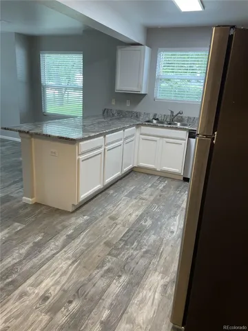 a kitchen with granite countertop a sink window and cabinets