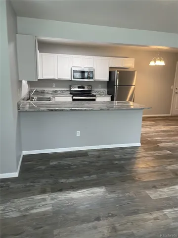 a view of kitchen with stainless steel appliances granite countertop a stove a sink and a microwave