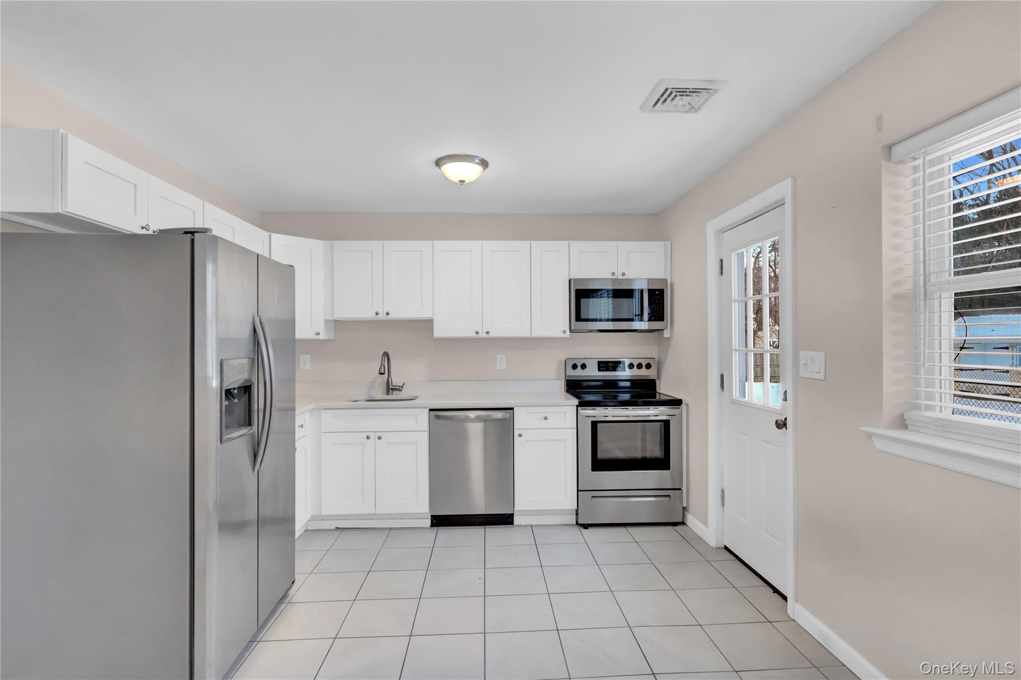 2 7th Street Center Moriches, NY 11934 - Photo 11 of 28 a kitchen with white cabinets and stainless steel appliances