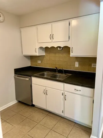 a kitchen with white cabinets and sink