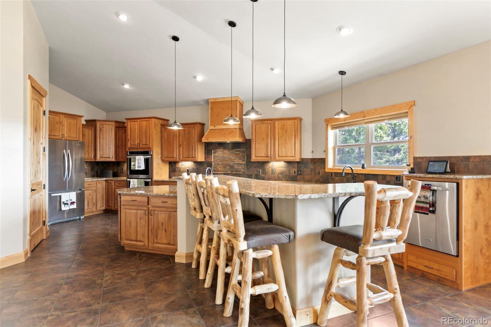 252 Running Elk Point Divide, CO 80814 - Photo 10 of 50 a kitchen with stainless steel appliances kitchen island granite countertop a refrigerator a stove a sink a dining table and chairs with wooden floor