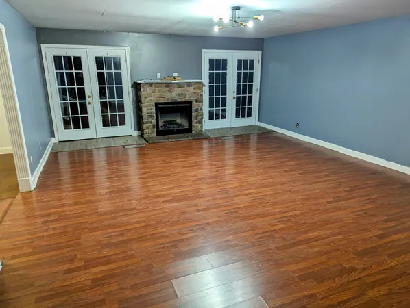 an empty room with wooden floor fireplace and windows