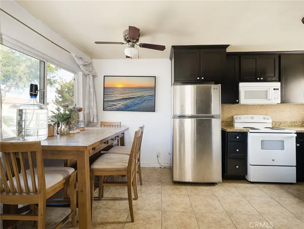 a kitchen with stainless steel appliances kitchen island granite countertop a refrigerator a stove a microwave oven with a dining table and chairs