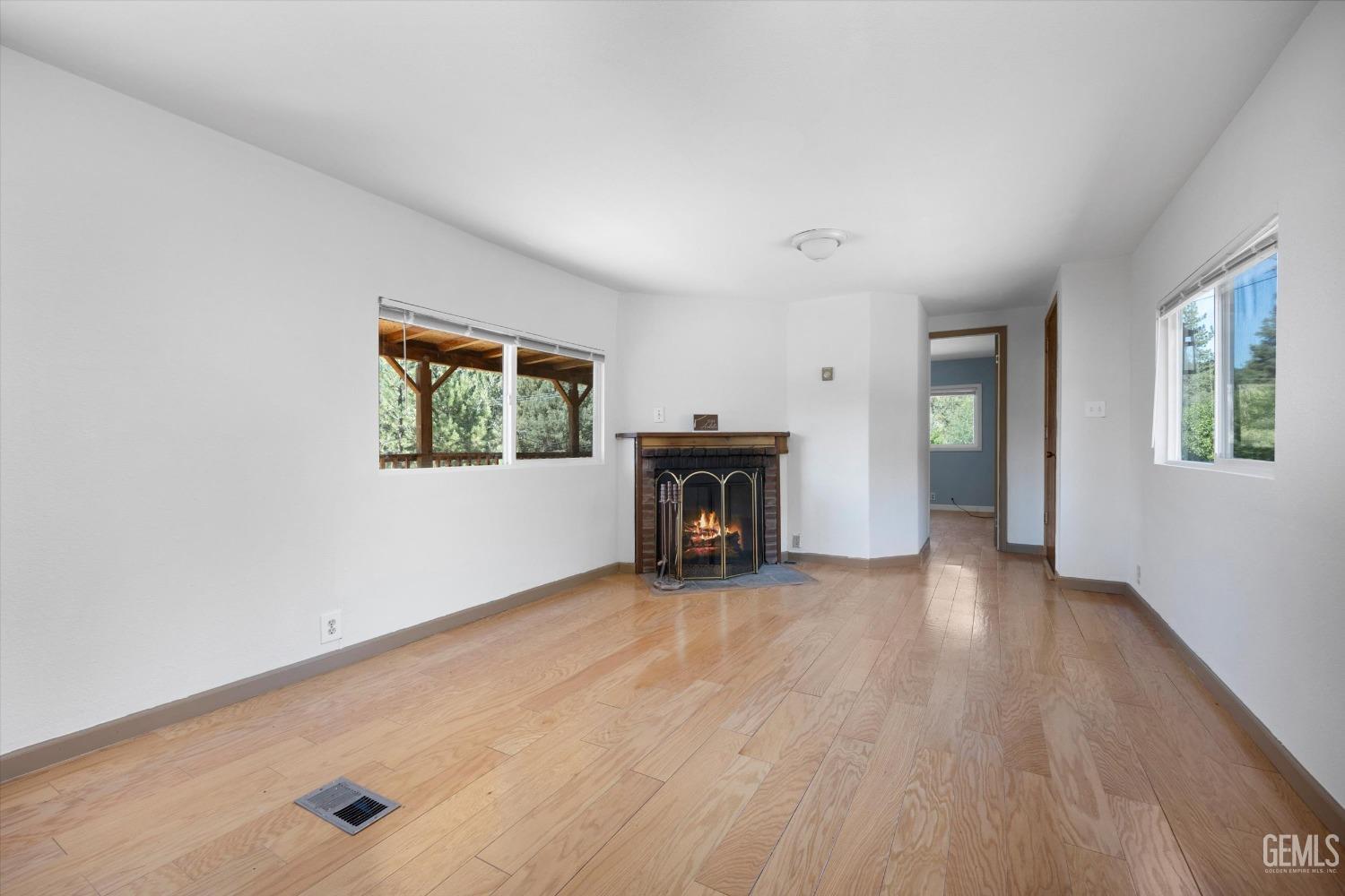 Undisclosed Address Pine Mountain Club, CA 93222 - Photo 13 of 22 an empty room with windows fireplace and wooden floor