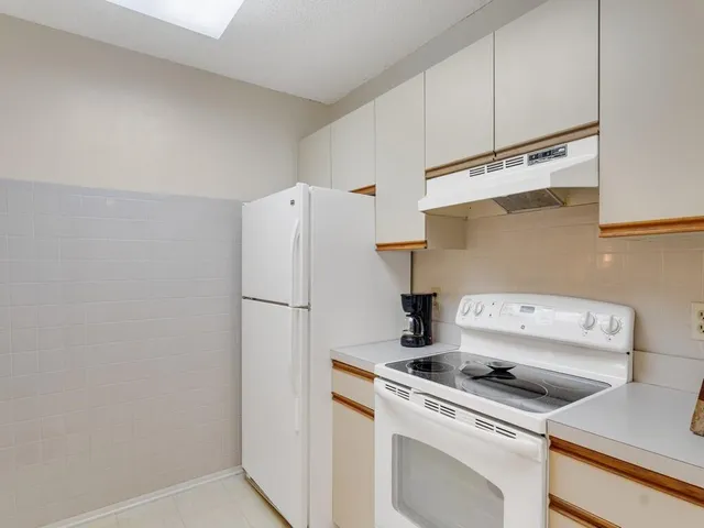 a white refrigerator freezer and a stove sitting inside of a kitchen