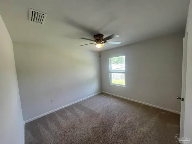 an empty room with windows and fan