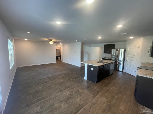 a large kitchen with stainless steel appliances kitchen island a large counter top and a wooden floors
