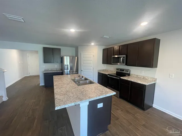a kitchen with granite countertop a stove and a wooden floor