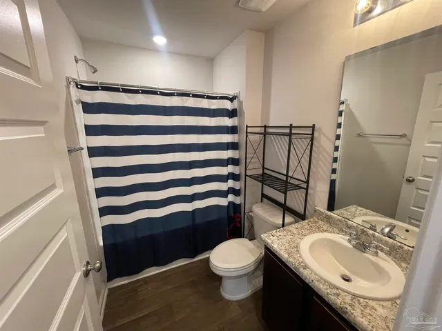a bathroom with a granite countertop toilet sink and mirror