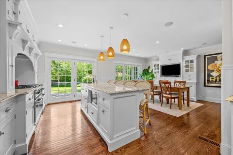 a kitchen with stainless steel appliances granite countertop a stove top oven a sink dishwasher a dining table and chairs with wooden floor